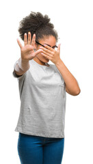 Sticker - Young afro american woman wearing glasses over isolated background covering eyes with hands and doing stop gesture with sad and fear expression. Embarrassed and negative concept.