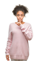 Poster - Young afro american woman wearing winter sweater over isolated background asking to be quiet with finger on lips. Silence and secret concept.