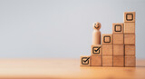 Wooden professional management figure smile and standing on second step of stair with tick checkmark for work task and project planing progressive concept.