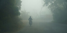 An Indian Man Riding A Bike At Early Morning On Foggy Road