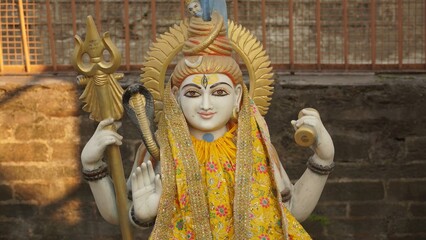 Wall Mural - closeup shot of sculpture of lord shiva wearing yellow cloth in temple