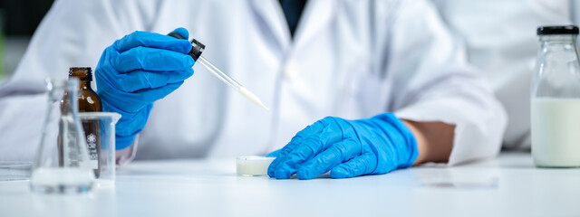 Poster - Close up of scientist or nutritionist dripping a sample of milk, fat or glucose in a test tube or beaker in laboratory, Expertise is working on lactose, protein experiment analysis or testing quality.