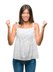 Poster - Young asian woman over isolated background celebrating surprised and amazed for success with arms raised and open eyes. Winner concept.