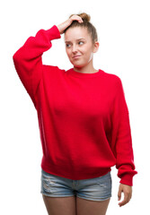 Wall Mural - Young blonde woman wearing bun and red sweater confuse and wonder about question. Uncertain with doubt, thinking with hand on head. Pensive concept.