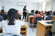 © EduLife Photos - Rearview of college students listening to lecturer in the classroom
