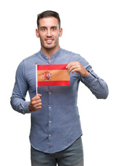 Sticker - Handsome young man holding a flag of Spain with a happy face standing and smiling with a confident smile showing teeth