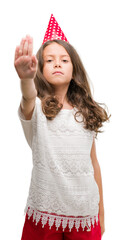 Poster - Brunette hispanic girl wearing birthday hat with open hand doing stop sign with serious and confident expression, defense gesture