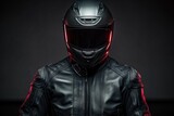 Fototapeta  - Man wearing a black leather motorcycle jacket and helmet on dark background.
