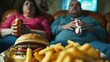 Overweight couple sitting on sofa, watching TV and eating fast food 
