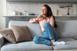 Content woman savoring coffee on comfortable couch
