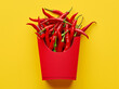 Creative red chili peppers packed in a french fries red paper box placed on a yellow background. Minimal chili food concept. Copy space.