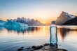 bottle of fresh mineral water in front of a mountain lake, epic sunlight