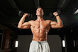 © Elena - The athlete with tanned skin and powerful arms is standing with dumbbells in his hands. His torso seems to embody strength and power, as he performs the exercises with ease and confidence.