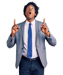 Canvas Print - Handsome african american man with afro hair wearing business jacket amazed and surprised looking up and pointing with fingers and raised arms.