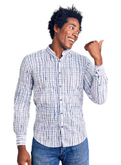 Wall Mural - Handsome african american man with afro hair wearing casual clothes smiling with happy face looking and pointing to the side with thumb up.