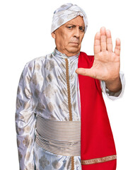 Wall Mural - Senior hispanic man wearing tradition sherwani saree clothes doing stop sing with palm of the hand. warning expression with negative and serious gesture on the face.