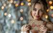 Valentines day concept. Beautiful young woman holding Love card. Golden bokeh lights background