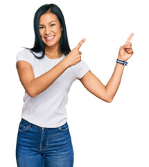 Wall Mural - Beautiful hispanic woman wearing casual white tshirt smiling and looking at the camera pointing with two hands and fingers to the side.