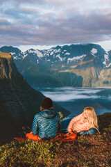 Wall Mural - Romantic couple in sleeping bags on  bivouac travel in Norway mountains with camping travel gear. Friends hiking enjoying fjord view, active vacations healthy lifestyle outdoor Valentines day holiday