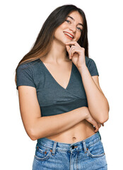 Poster - Young beautiful teen girl wearing casual crop top t shirt looking confident at the camera with smile with crossed arms and hand raised on chin. thinking positive.