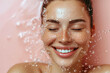 © ronstik - skin care and hydration concept. smiling woman with eyes closed and water splash around the face on light pink background
