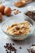 © Lazylizard - Creamy cookie dough in a mixing bowl with chocolate chips, surrounded by baking ingredients like eggs and flour on a marble kitchen counter..