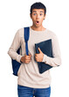 Young african amercian man wearing student backpack holding binder scared and amazed with open mouth for surprise, disbelief face