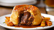 Traditional British dish steak and kidney pudding in suet pastry with gravy served on a plate. Delicious hearty comfort food