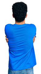 Wall Mural - Young arab man with beard wearing casual blue t shirt hugging oneself happy and positive from backwards. self love and self care