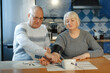 © Ala - An elderly man measures his wife's blood pressure and presses the button on the tonometer.