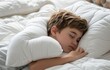 © olegganko - a small boy sleeping on a white pillow