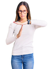 Wall Mural - Beautiful brunette young woman wearing casual white sweater and glasses doing time out gesture with hands, frustrated and serious face