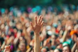 Fototapeta  - Raised hand with blurred crowd at outdoor concert