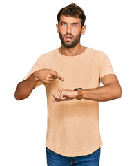 Poster - Handsome young man with beard wearing casual tshirt in hurry pointing to watch time, impatience, upset and angry for deadline delay