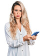 © Krakenimages.com - Young blonde woman using smartphone depressed and worry for distress, crying angry and afraid. sad expression.