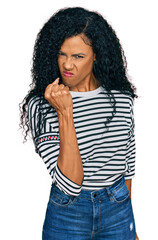 Wall Mural - Middle age african american woman wearing casual clothes angry and mad raising fist frustrated and furious while shouting with anger. rage and aggressive concept.