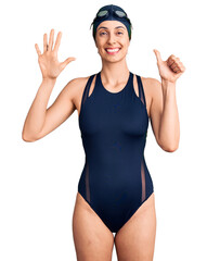 Canvas Print - Young beautiful hispanic woman wearing swimwear and swimmer glasses showing and pointing up with fingers number six while smiling confident and happy.