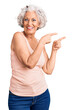 © Krakenimages.com - Senior grey-haired woman wearing casual clothes smiling and looking at the camera pointing with two hands and fingers to the side.