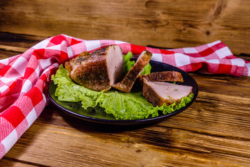 Wall Mural - Slices of baked pork meat and lettuce leaves on a black plate