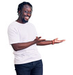 © Krakenimages.com - Young african american man with braids wearing casual white tshirt inviting to enter smiling natural with open hand