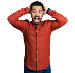 Poster - Young hispanic man with beard wearing casual shirt crazy and scared with hands on head, afraid and surprised of shock with open mouth