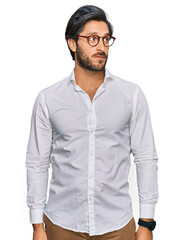 Young hispanic man wearing business shirt and glasses smiling looking to the side and staring away thinking.