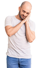 Poster - Young handsome man wearing casual t shirt sleeping tired dreaming and posing with hands together while smiling with closed eyes.