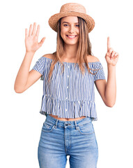 Wall Mural - Young beautiful girl wearing hat and t shirt showing and pointing up with fingers number six while smiling confident and happy.