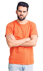 Wall Mural - Young handsome man with beard wearing casual t-shirt skeptic and nervous, disapproving expression on face with crossed arms. negative person.