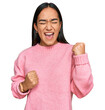 © Krakenimages.com - Young asian woman wearing casual winter sweater celebrating surprised and amazed for success with arms raised and eyes closed. winner concept.