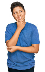 Sticker - Teenager hispanic boy wearing casual clothes with hand on chin thinking about question, pensive expression. smiling with thoughtful face. doubt concept.