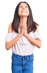 Wall Mural - Beautiful child girl wearing casual clothes begging and praying with hands together with hope expression on face very emotional and worried. begging.