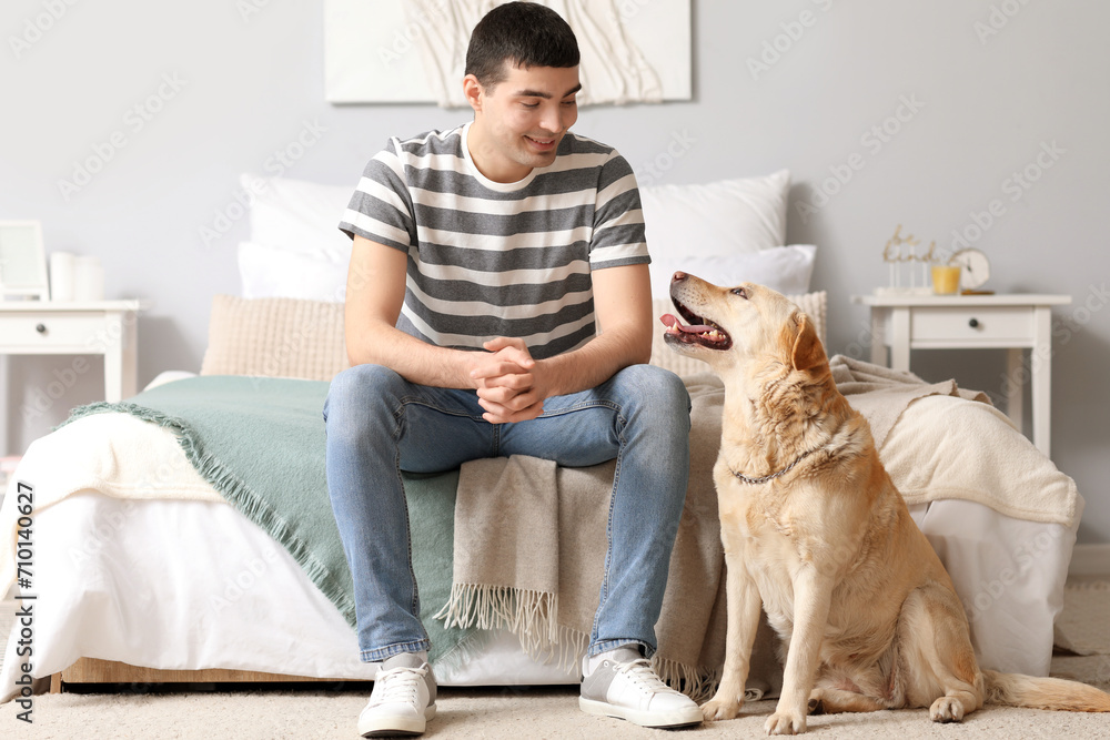 Young man with Labrador dog in bedroom