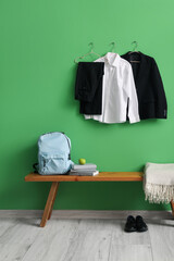 Wall Mural - Bench with backpack, shoes and stylish school uniform hanging on green wall in room